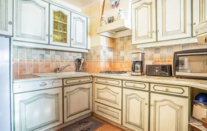 A kitchen with white cabinetry, a gas stove, a coffee maker, a toaster, and a microwave. - Lovely apartment in binic-étables-sur-mer (Binic-Étables-Sur-Mer)