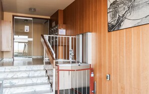 Eine Hotelhalle mit Marmorstufen, einer Holzwand, einem Sicherheitstor und einem Schwarz-Weiß-Kunstwerk.