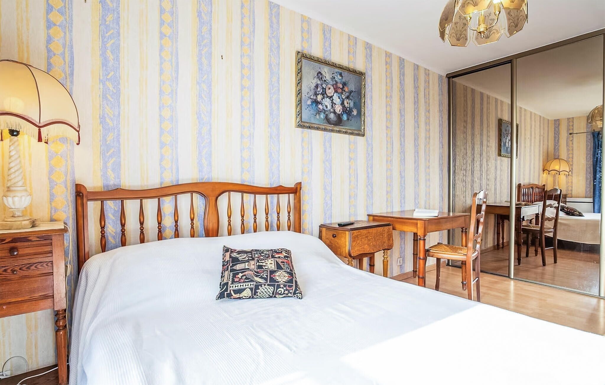 Une chambre d’hôtel avec un lit, un bureau, une chaise, une lampe et un tableau au mur.