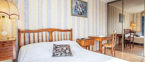 Une chambre d’hôtel avec un lit, un bureau, une chaise, une lampe et un tableau au mur.