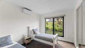 Un dormitorio con dos camas, una mesita de noche y una ventana con vista a un jardín.