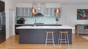 Una cocina moderna con una isla central, electrodomésticos de acero inoxidable e iluminación colgante.