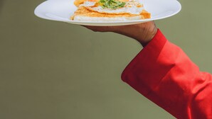 Iemand houdt een witte schaal vast met eten erop.