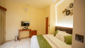 Een hotelkamer met een bed, een televisie, een bureau en een decoratie aan de muur.