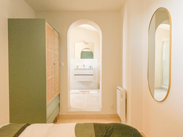Habitación de hotel con cama, espejo, armario y vistas al baño.