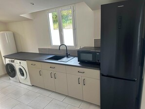 A modern kitchen with a built-in washing machine, a black refrigerator, and a microwave. - Nice holiday home with pool and wide views (Saint-Julien-le-Montagnier)