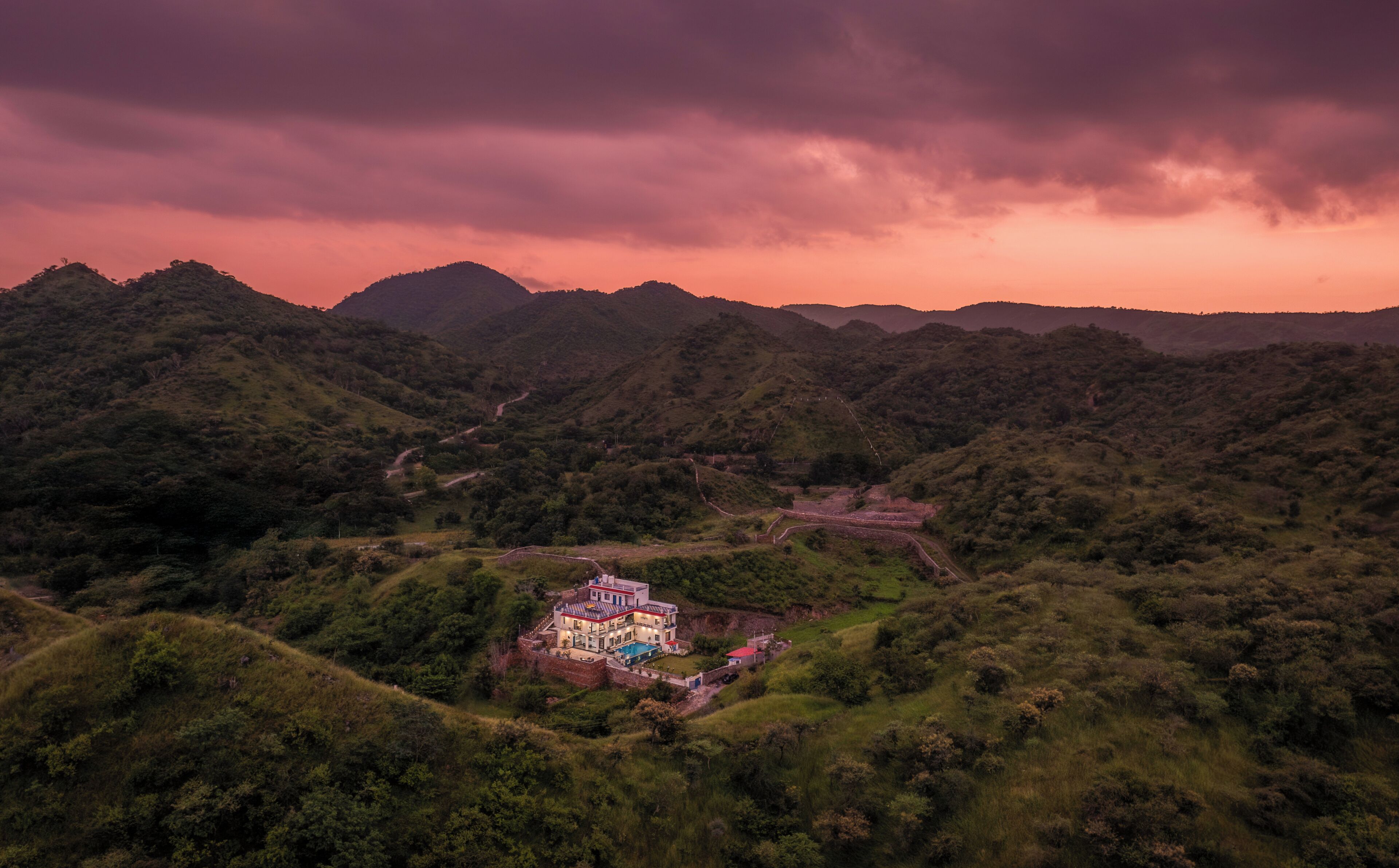A house with a swimming pool surrounded by lush greenery and hills.