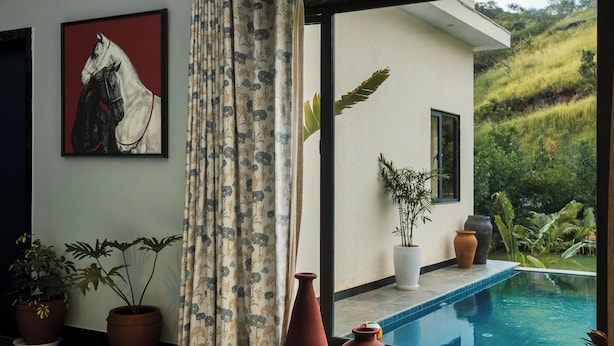 Un interior moderno con un amplio ventanal que da a una piscina y jardín.