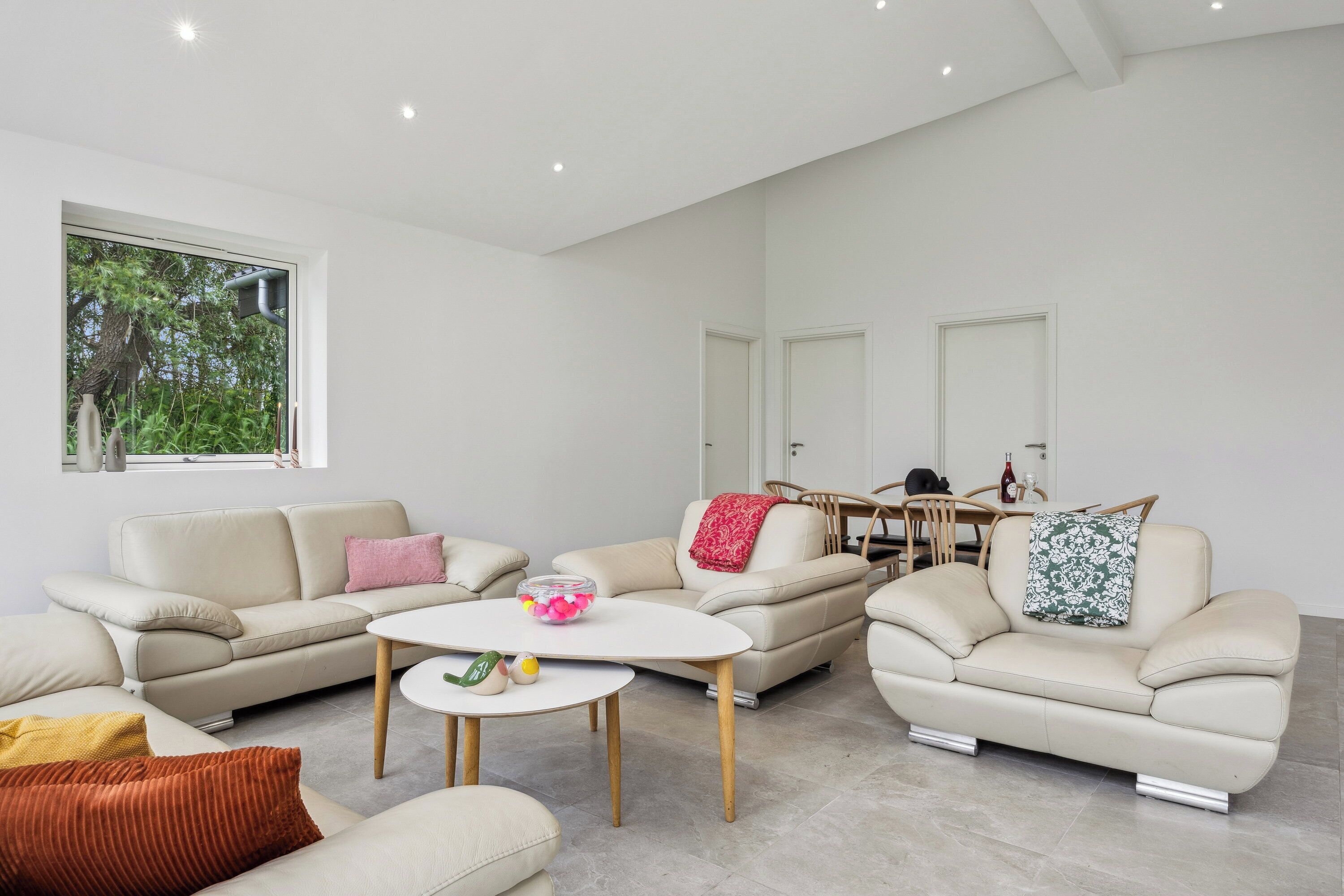 A modern living room with a sofa set, a coffee table, and a dining area with chairs and a table.