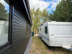 A mobile home adjacent to a building with a window and a door.
