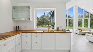 A modern kitchen with white cabinets, a wooden countertop, and a large window. - New & inviting holiday home near beach and nature (Væggerløse)