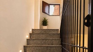 Una escalera con escalones de granito, una planta en maceta y un aplique de pared.