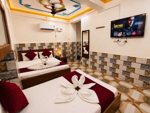 Habitación de hotel con dos camas, televisión y ventilador de techo.