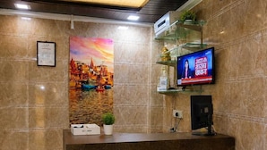 Un área de recepción con televisor, un cuadro enmarcado y un mostrador.