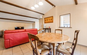 A dining area with a wooden table and chairs, a red sofa, and a television in the background. - Lovely apartment in épargnes with WiFi (Épargnes)
