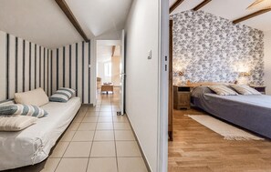 A narrow hallway leading to a bedroom with a bed, a nightstand, and a wall with floral wallpaper. - Lovely apartment in épargnes with WiFi (Épargnes)