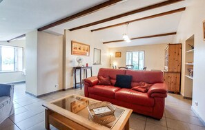 A living room with a red leather sofa, a glass coffee table, and a dining area in the background. - Lovely apartment in épargnes with WiFi (Épargnes)