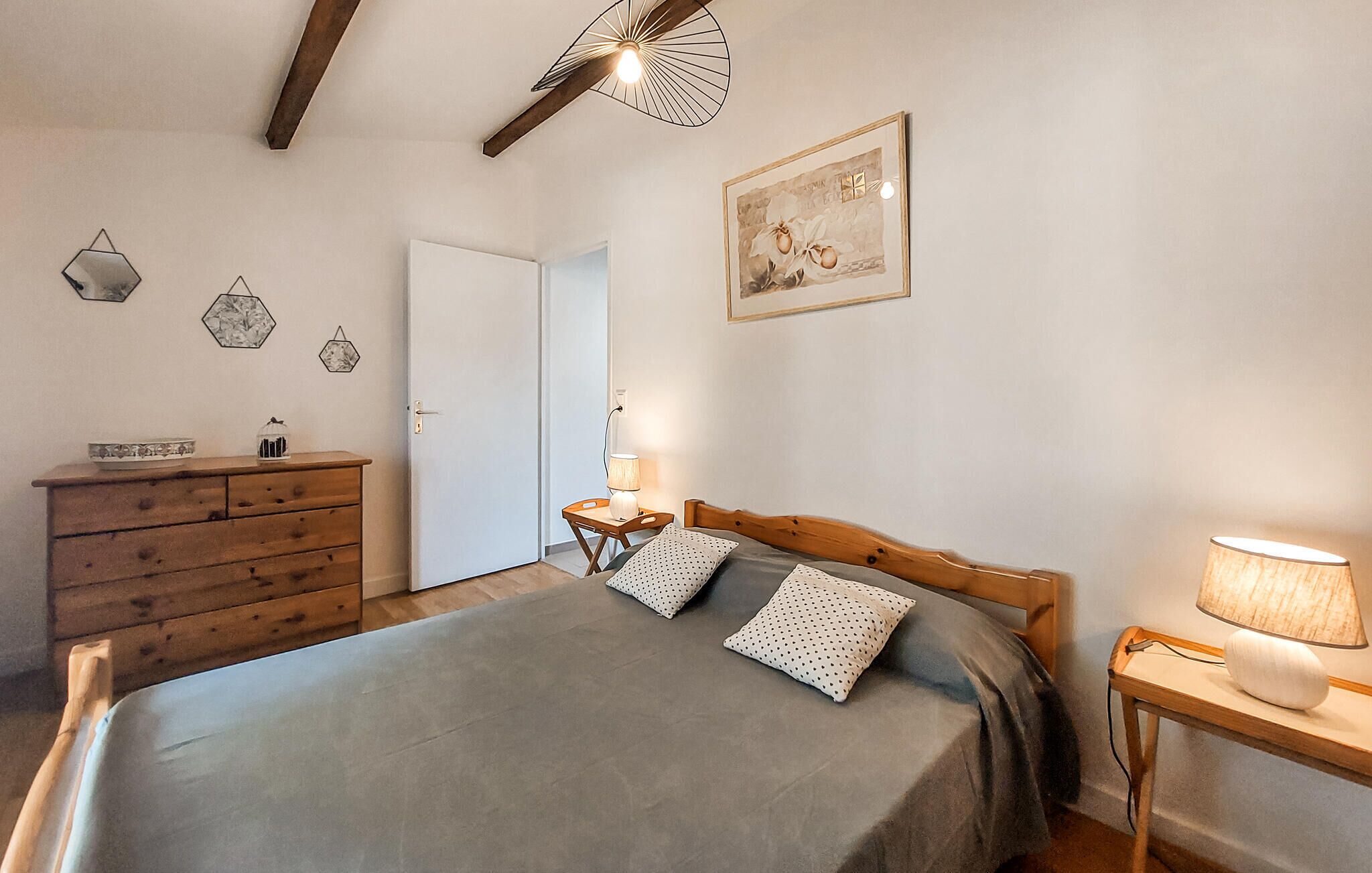 Une chambre à coucher avec un lit, une commode en bois, des tables de chevet et des œuvres d’art murales.