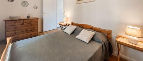 Une chambre à coucher avec un lit, une commode en bois, des tables de chevet et des œuvres d’art murales.