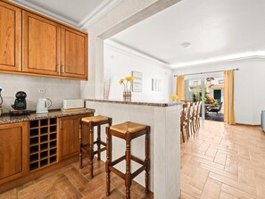 Una cocina con armarios de madera, encimera de granito y una zona de bar con taburetes.