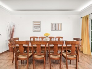 Un comedor con una mesa y sillas de madera, un jarrón con flores amarillas y arte abstracto en las paredes.