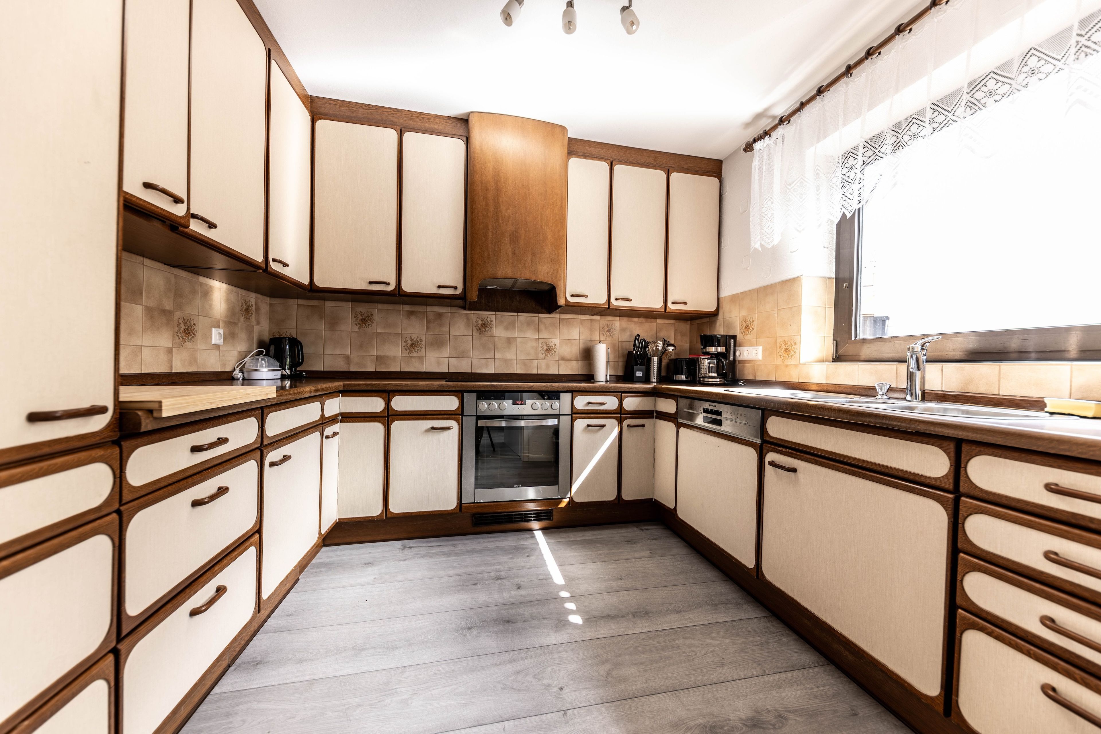 A kitchen with wooden cabinets, a built-in oven, and a stainless steel sink.