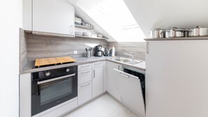 Een moderne keuken met dakraam, inbouwoven en roestvrijstalen apparatuur.