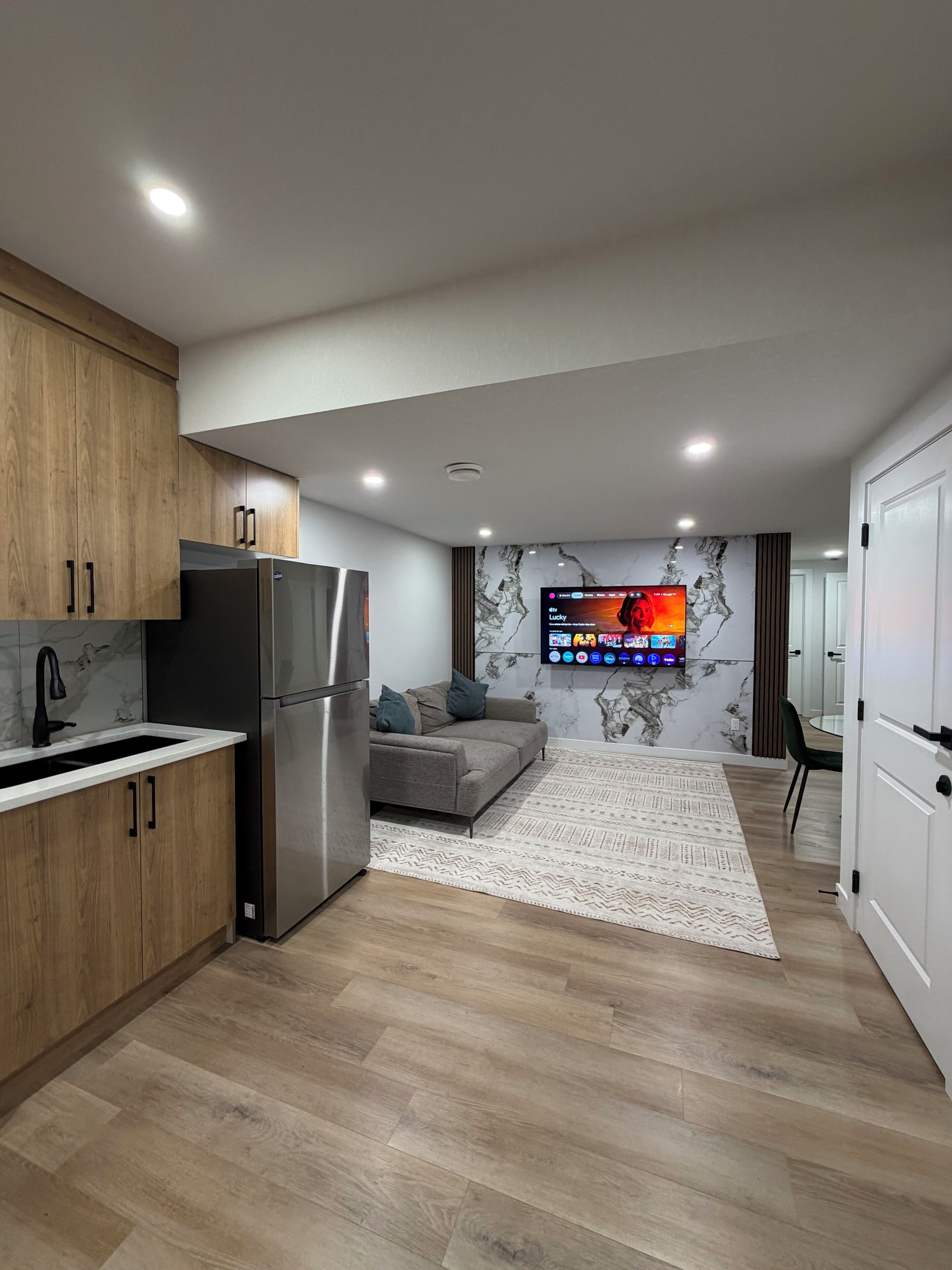 A modern kitchen with a built-in refrigerator, wooden cabinets, and a marble backsplash.