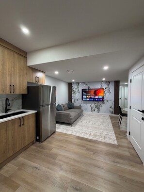 A modern kitchen with a built-in refrigerator, wooden cabinets, and a marble backsplash. - The Quarry Retreat | Modern 2-Bedroom Luxury Suite (Edmonton)