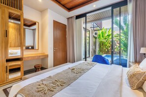 Ein modernes Hotelzimmer mit einem großen Bett, einem Holzschrank, einem Badezimmer und Blick auf einen Pool und Grünflächen.
