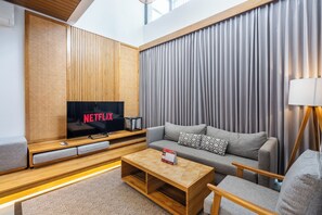 A modern living room with a flat-screen TV, a sofa, a coffee table, and a lamp. - The Louver Canggu Exotic Bali Properties (Canggu)
