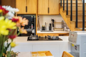 A kitchen with wooden cabinets, a gas stove, a coffee machine, and a dishwasher. - The Louver Canggu Exotic Bali Properties (Canggu)