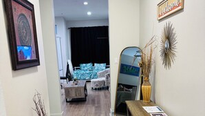 Un interior moderno con un banco de madera, un letrero de bienvenida, un espejo y una obra de arte enmarcada.