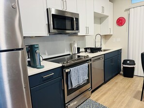 Een moderne keuken met roestvrijstalen apparatuur, witte kasten, een zwart aanrecht en een kamerkleed met een patroon.