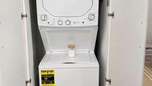 Una lavadora portátil blanca con panel de control, dispensador de detergente e indicador de nivel de agua.