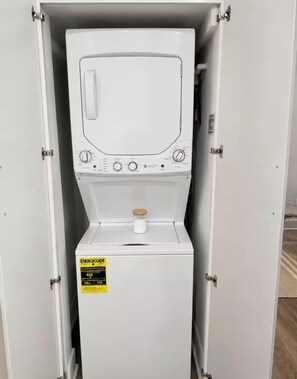 Eine weiße, tragbare Waschmaschine mit Bedienfeld, Dosierfach für Waschmittel und Wasserstandsanzeige.