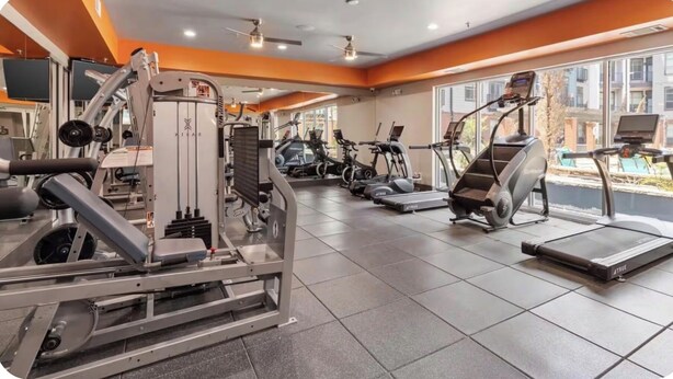 Un gimnasio con diferentes equipos de ejercicio, incluyendo cintas de correr y máquinas de pesas.