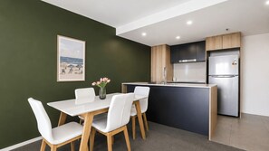Eine moderne Küche mit integrierter Kochinsel, weißen Stühlen, einer Blumenvase und einem gerahmten Bild an der Wand.