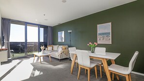 Ein modernes Wohnzimmer mit einer Couch, Sesseln, einem Esstisch und Blick ins Freie.