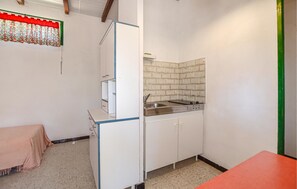 Eine kleine Küche mit Spüle, Schränken und einer gefliesten Spritzschutzwand.