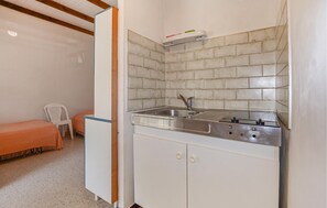 Eine kleine Küchenzeile mit Spüle, Arbeitsplatte und Schrank.
