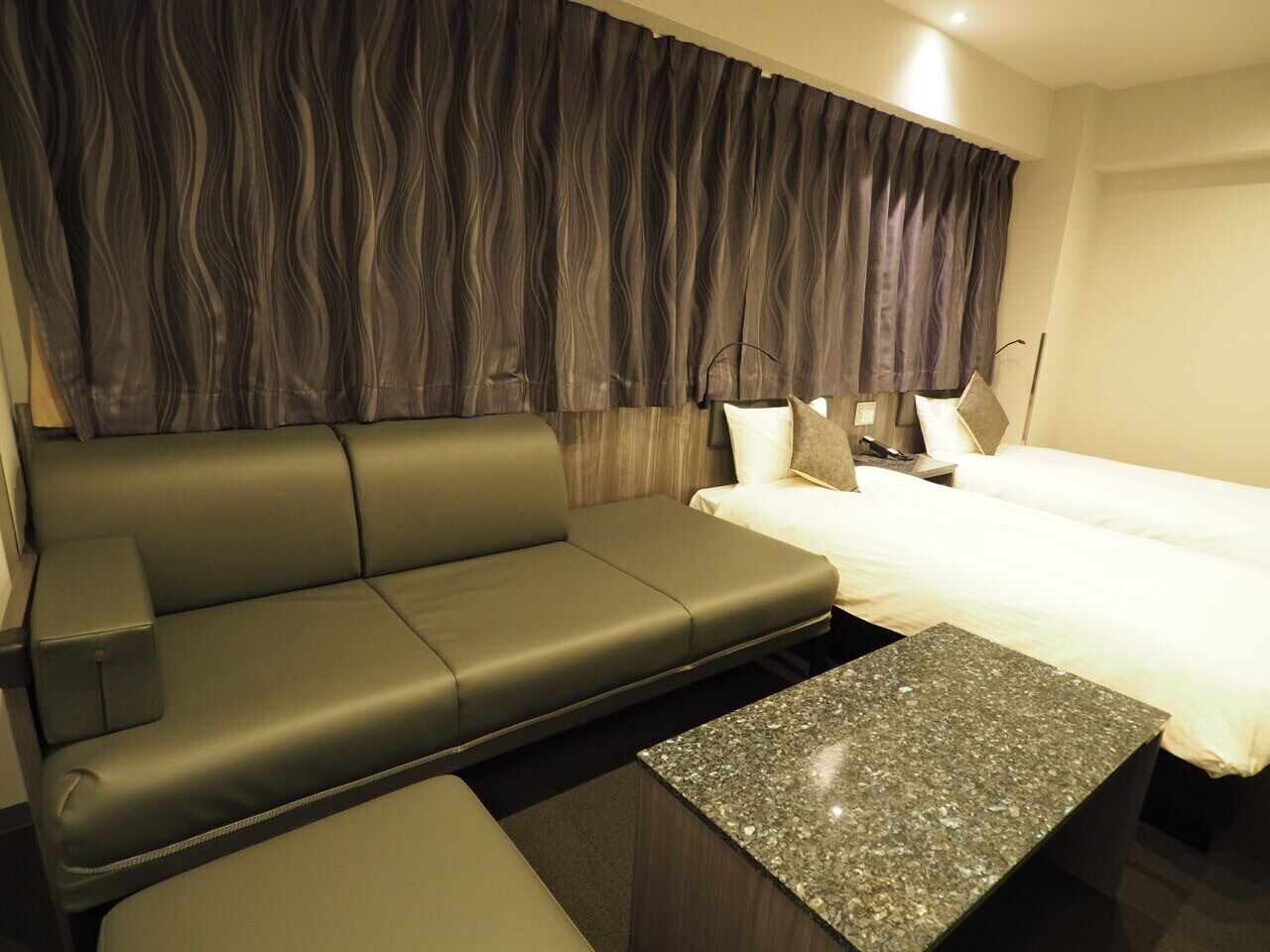 Une chambre d’hôtel moderne avec un canapé, un lit et une petite table.