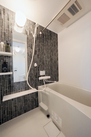 A modern bathroom with a bathtub, a shower area, and a mirror. - Hotel BB (Ota City)