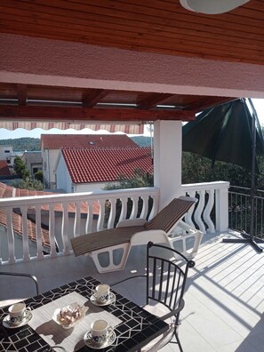 Ein Balkon mit einem Tisch für zwei Personen, einem Stuhl und Blick auf Gebäude mit roten Dächern.