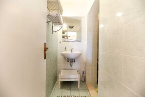 A narrow bathroom with a white sink, a mirror above it, and a towel rack. - Apartments Melita - Comfort Two Bedroom Apartment With Terrace and Sea View (Zadar)