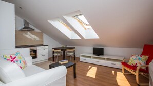 Een moderne woonruimte met een vide, dakramen, een kitchenette en een televisie.