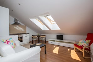 A modern living space with a loft bedroom, skylights, a kitchenette, and a TV. - Apartments Nina - One-bedroom Apartment (Dubrovnik)