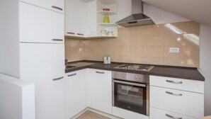 Een kleine keuken met witte kasten, een fornuis en een afzuigkap.