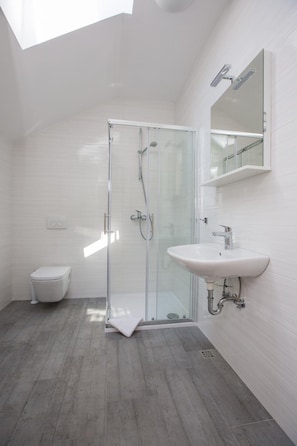 A modern bathroom with a glass shower enclosure, a white sink, and a toilet. - Apartments Nina - One-bedroom Apartment (Dubrovnik)