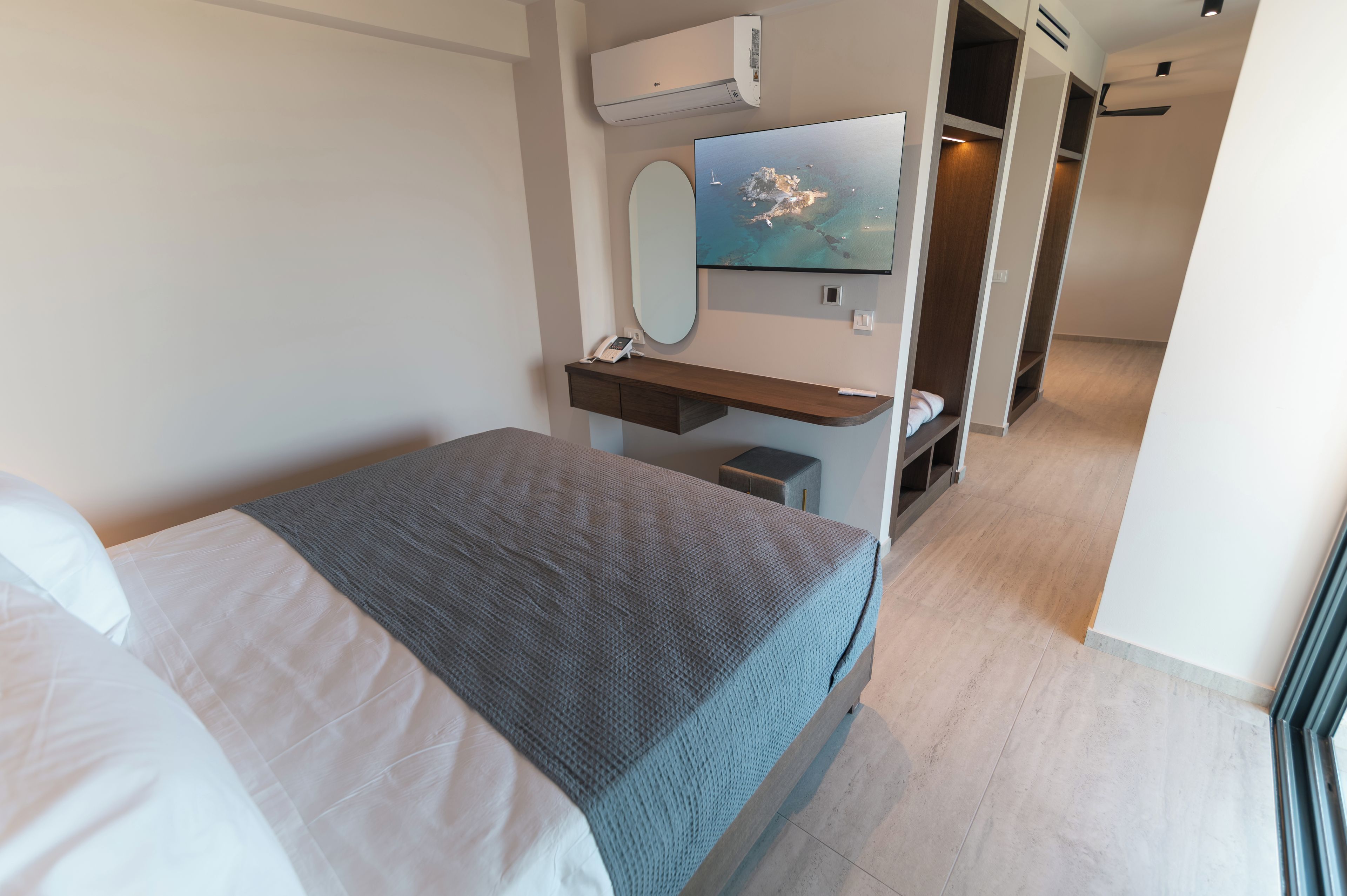 Ein modernes Hotelzimmer mit Bett, Schreibtisch, Spiegel, Fernseher und Meerblick.